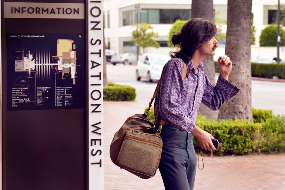 Stylish young man with bag waits at Union Station in Los Angeles, embodying urban exploration.